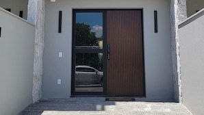 A modern two-story building with a flat roof, large windows, and a central entrance with a sliding door. - Tranquil 3 Suite Home With Ocean Breeze in Prime Location! (Florianópolis)