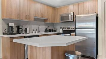 A modern kitchen with wooden cabinets, a stainless steel refrigerator, a microwave, a coffee maker, and a dishwasher.
