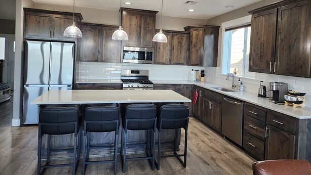Una cocina moderna con armarios de madera oscura, electrodomésticos de acero inoxidable y una isla central con taburetes de bar.
