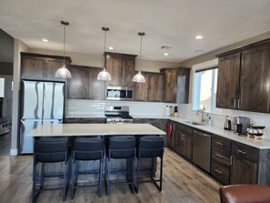 A modern kitchen with dark wood cabinets, stainless steel appliances, and a central island with bar stools.