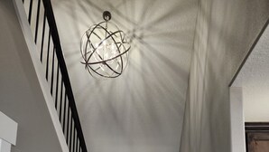 Un pasillo con un banco, una escalera y un candelabro.