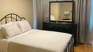 A bedroom with a bed, a ceiling fan, a dresser, and a mirror. - Vacation Rental In Brooklyn - The Fulton (Brooklyn)
