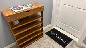 A wooden storage unit with multiple shelves and a magazine on top, next to a door with a 'welcome' mat. - Vacation Rental In Brooklyn - The Fulton (Brooklyn)