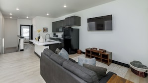 A modern living room with a grey sofa, a coffee table, and a TV mounted on the wall.