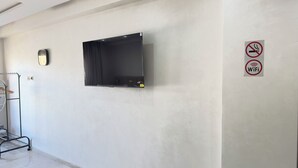 Una stanza con TV a schermo piatto montata, un cartello che indica divieto di fumo e un segnale WiFi sul muro.