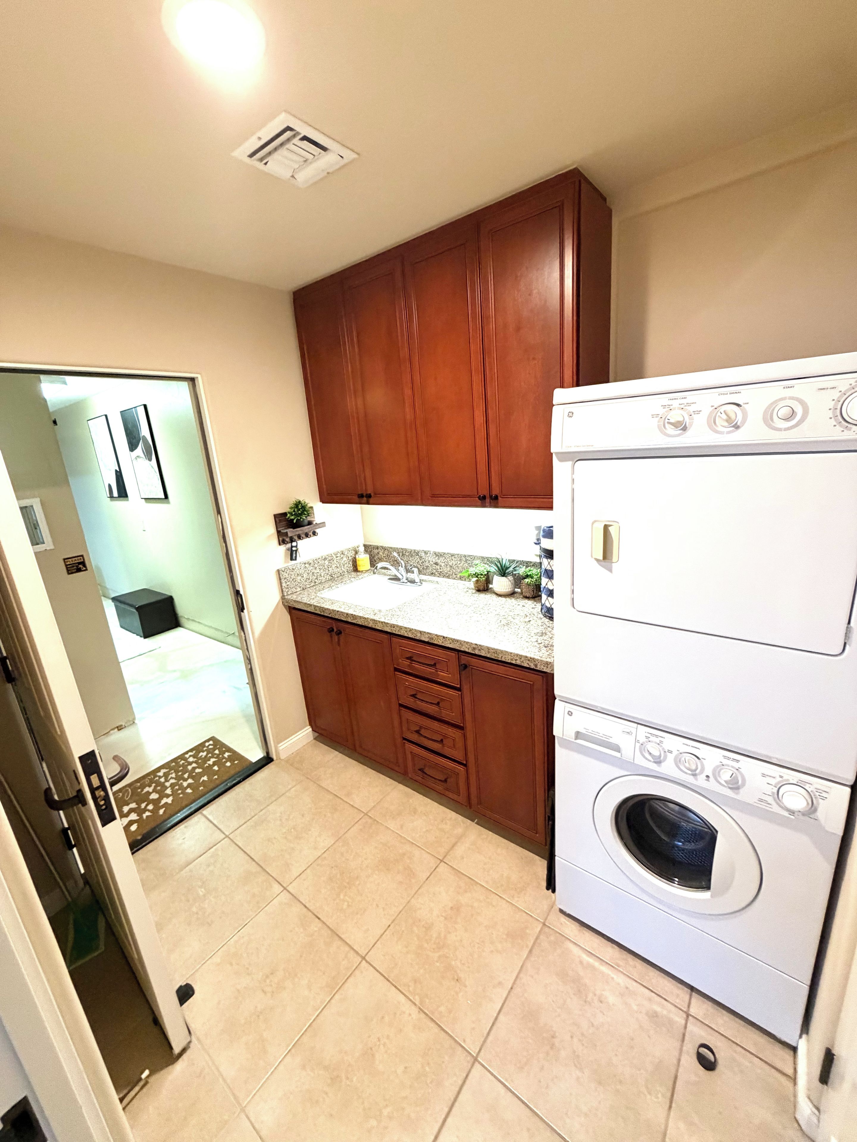 Une cuisine avec des meubles de rangement en bois, un plan de travail et un lave-linge et un sèche-linge intégrés.