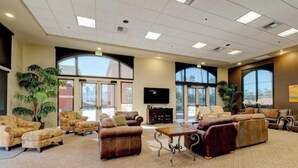 A spacious lobby with multiple seating areas, large windows, and a flat-screen TV.