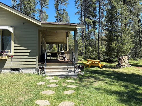 A house with a porch, a picnic table, and a stack of firewood.