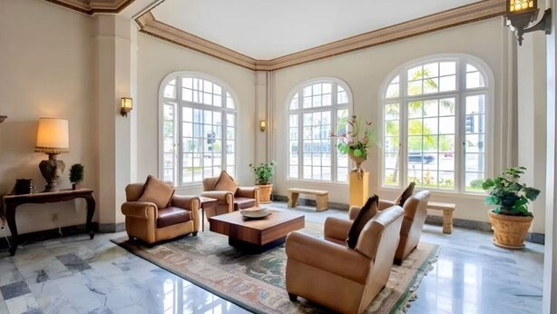 Un hall d’entrée spacieux, doté de grandes fenêtres en arc de cercle, de canapés en cuir, d’une table basse et d’un sol en marbre.
