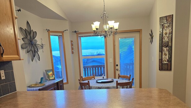 A kitchen with wooden cabinets, a stainless steel dishwasher, a granite countertop, and a dining area with a view. - Pet friendly 2 bedroom and full bathroom with soaker tub close to Westerner. (Red Deer)