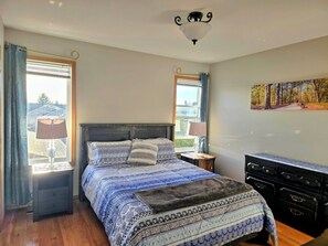 A bedroom with a bed, nightstands, a dresser, and a painting on the wall. - Pet-friendly 2-bedroom close to Westerner. (Red Deer)