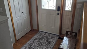 A room with a wooden floor, a patterned rug, a door with a glass panel, and a small table with a chair. - Pet friendly 2 bedroom and full bathroom with soaker tub close to Westerner. (Red Deer)