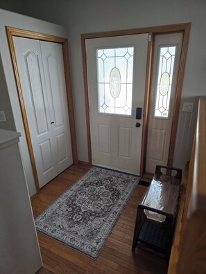 A room with a wooden floor, a patterned rug, a door with a glass panel, and a small table with a chair. - Pet friendly 2 bedroom and full bathroom with soaker tub close to Westerner. (Red Deer)