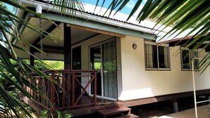 A building with a covered porch, a staircase leading to a door, and a view of the surrounding greenery. - Charming 1BR Guesthouse in Beautiful Moorea (Haapiti Tiahura)