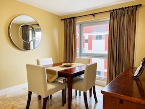 Uma sala de jantar com mesa, cadeiras, espelho e cortinas.