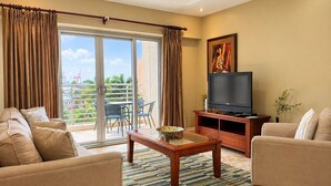 Una sala de estar con sofá, sillón, televisor y un balcón con vistas.
