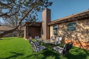 A modern house with a brick exterior, a glass dining table, and outdoor furniture.