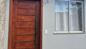 Una casa con puerta de madera, una ventana y el número 476 en la pared.