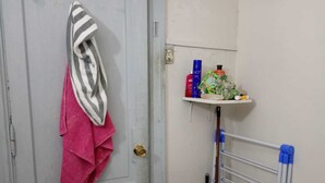 Ein Badezimmer mit einem über einer Tür hängenden Handtuch, einem Ablagefach mit Toilettenartikeln und einem Wäscheständer.