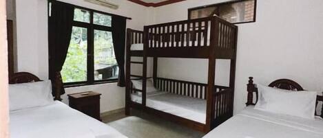 A room with two wooden beds, a ceiling fan, and a window with curtains.