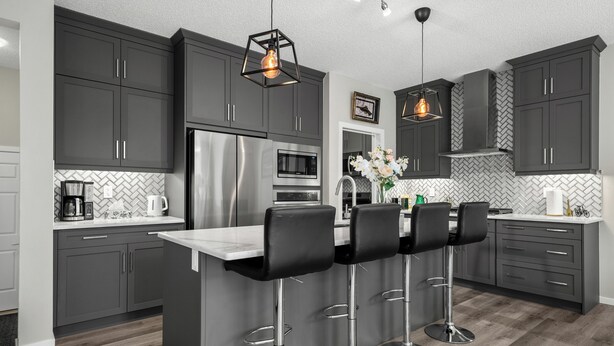 A modern kitchen with dark cabinets, stainless steel appliances, and a central island with bar stools.