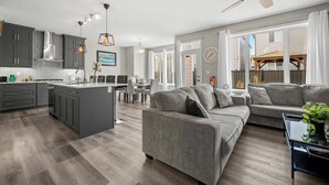 A modern kitchen with grey cabinets, a central island, and pendant lighting.