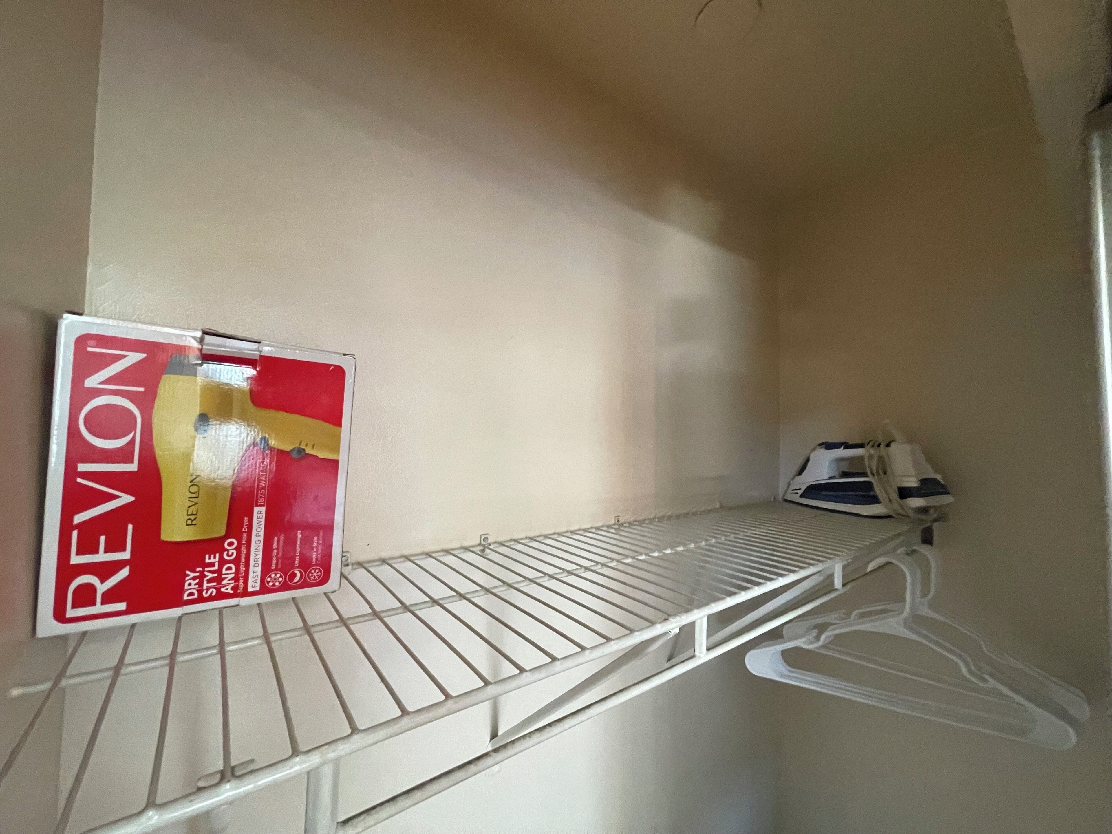 Une étagère de rangement contenant une boîte de produits capillaires Revlon et un appareil électroménager blanc.