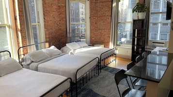 Une chambre d’hôtel avec deux lits simples, un bureau, une chaise et une plante en pot.