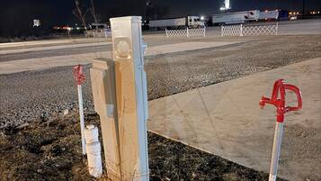 Um estacionamento com uma barreira de concreto, uma caminhonete branca e um hidrante vermelho.