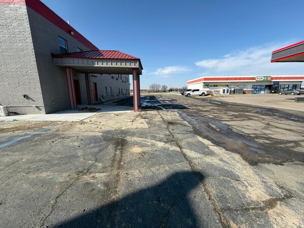 Un parking avec un bâtiment sur la gauche et une station-service sur la droite.