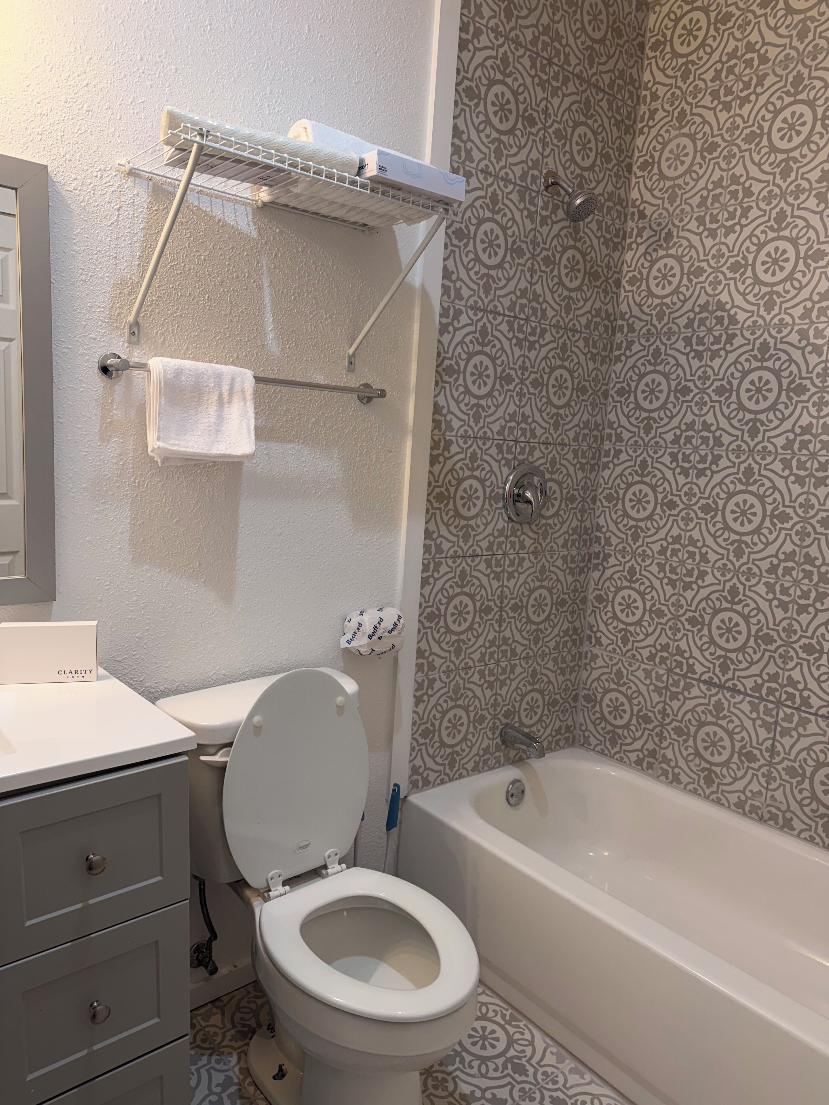 Un baño con inodoro, bañera y pared de ducha con diseño.