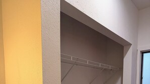 A room with a grey carpet, a white door, and a white wall with a grey textured section.