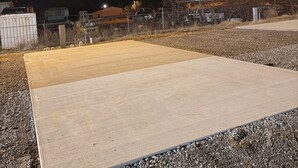 An outdoor area with a concrete platform, gravel ground, and a fence.