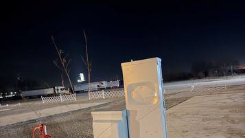 A parking lot at night with a few trucks and a white fence.