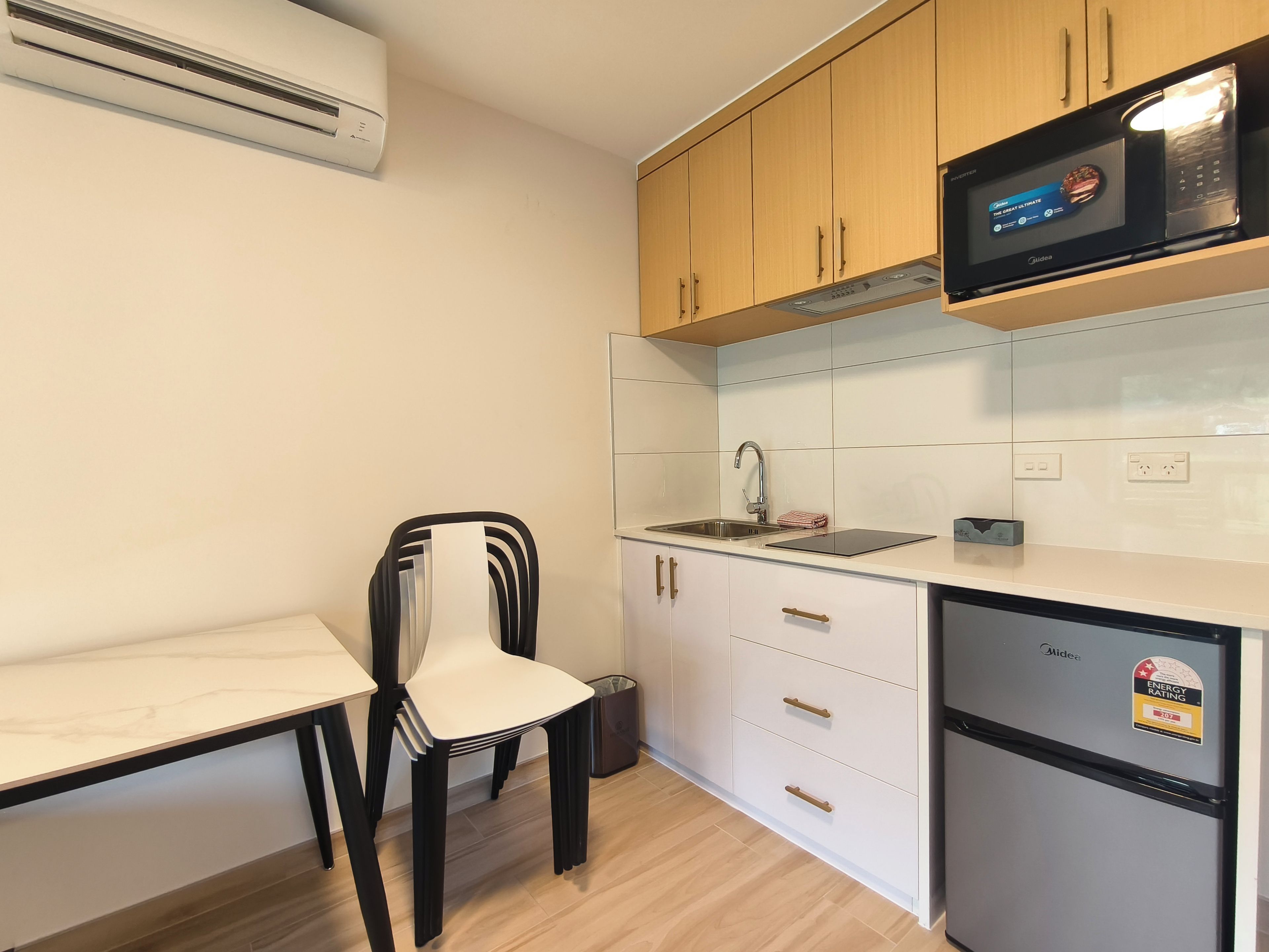 A compact kitchen with white cabinets, a black countertop, a built-in microwave, and a stainless steel sink.