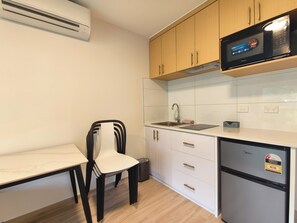 A compact kitchen with white cabinets, a black countertop, a built-in microwave, and a stainless steel sink.