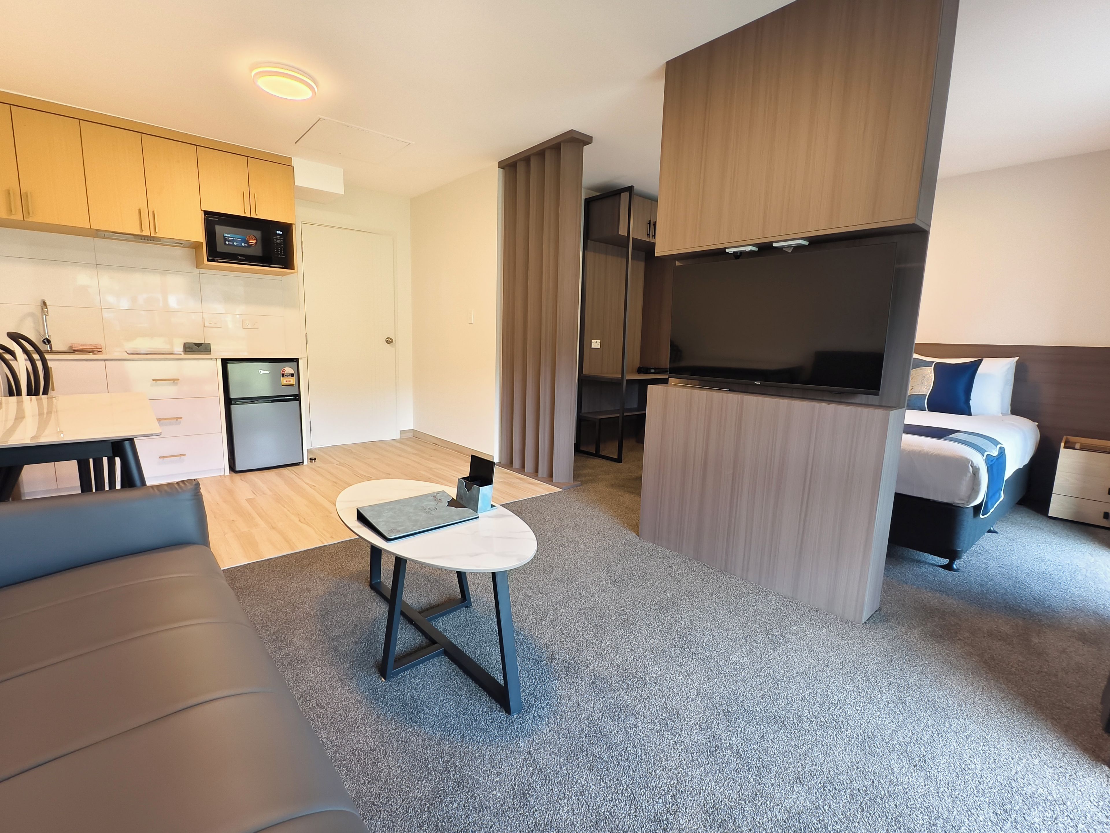 A compact living space with a kitchenette, a dining area, a seating area, and a bedroom.