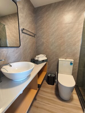 Un baño moderno con un lavamanos blanco, un inodoro y un espejo.
