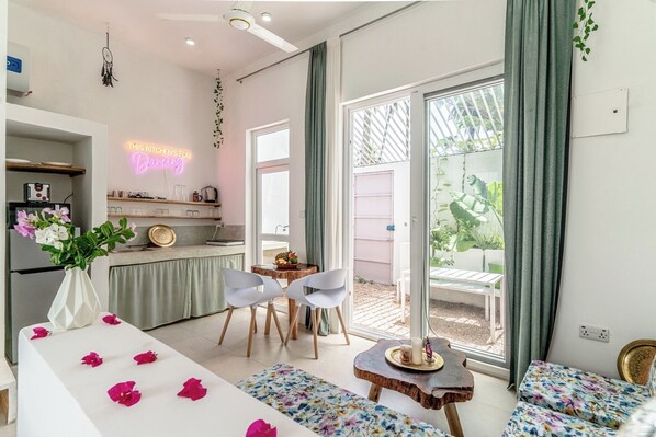 Une cuisine moderne avec un néon, un coin repas avec des chaises et une vue sur l’extérieur.
