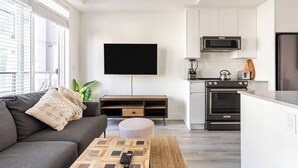 Una sala de estar moderna con un sofá gris, una mesa de centro y un televisor de pantalla plana montado en la pared.