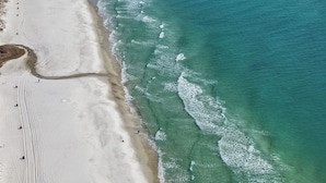 Vista aérea de una playa con aguas turquesas cristalinas y una orilla arenosa.