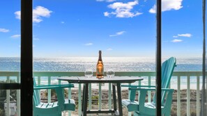 A balcony with a table and chairs overlooking a beach. - Beachfront Escape with Pool and Gulf Views (Panama City Beach)
