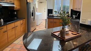 Una cocina moderna con armarios de madera, un refrigerador de acero inoxidable, horno empotrado y un amplio ventanal que proporciona luz natural.
