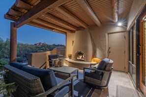 An outdoor patio with wicker furniture, a stone fireplace, and a view of a mountainous landscape. - Near Boulder Resort & Spa, Greens Space & Views, Covered Patio w/Grill (Scottsdale)