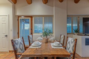 A dining room with a wooden table set for six, flanked by chairs with patterned upholstery. - Near Boulder Resort & Spa, Greens Space & Views, Covered Patio w/Grill (Scottsdale)