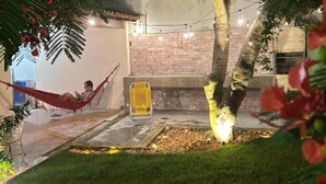 A hammock under a tree, a brick wall, and string lights.