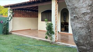 A two-story house with a covered patio, a small garden, and a visible door leading to the interior.