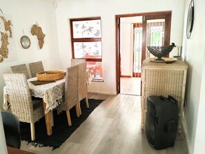 Ein Essbereich mit Korbstühlen, einem Tisch mit gemustertem Tischlauf und einem Korb.