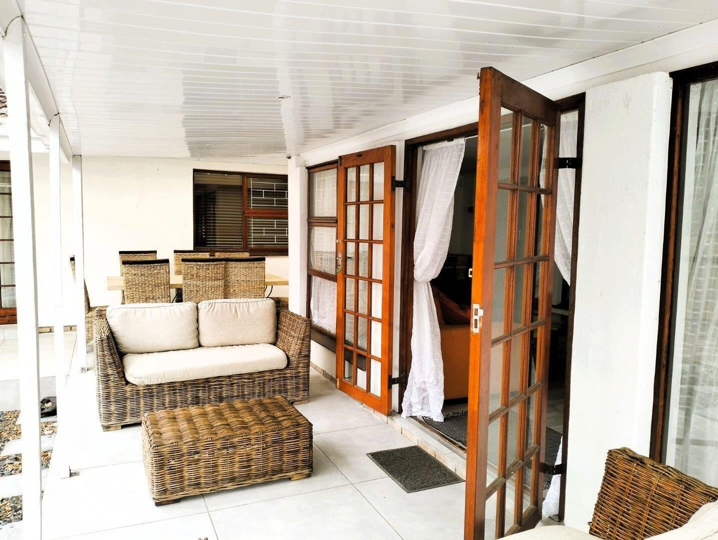 A room with a wicker sofa, a matching ottoman, and a sliding glass door leading to a balcony.
