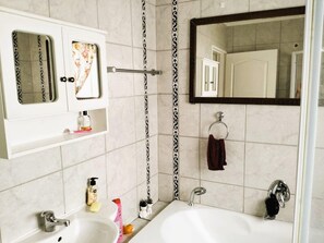 Ein Badezimmer mit einem weißen Waschbecken, einem Spiegel, einem Handtuchhalter und einer Badewanne.